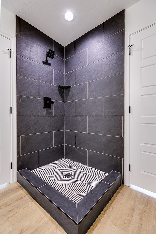 bathroom with hardwood / wood-style flooring and a tile shower