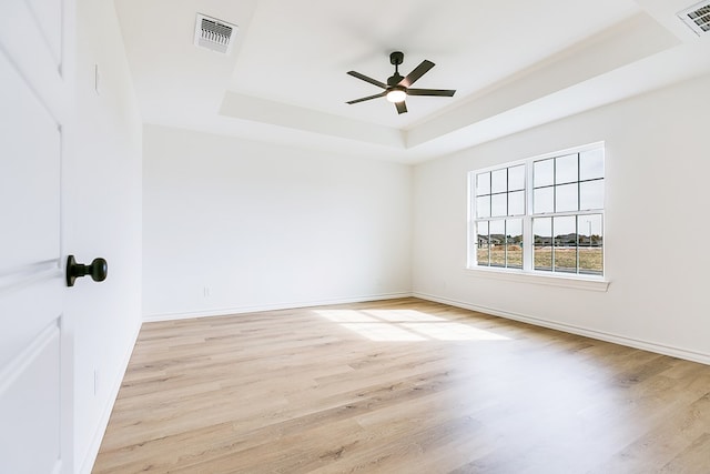 unfurnished room featuring ceiling fan, a raised ceiling, and light hardwood / wood-style flooring