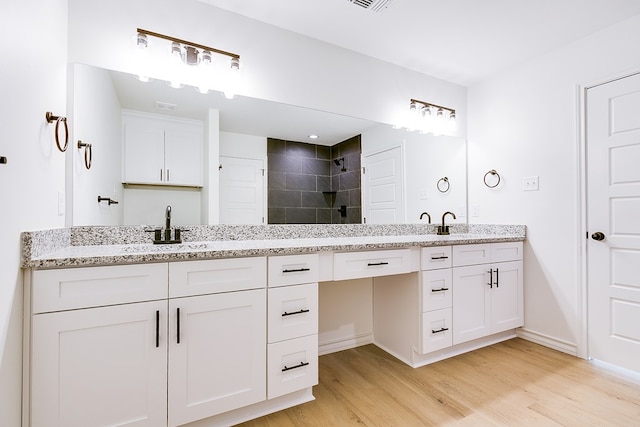 bathroom with vanity, hardwood / wood-style flooring, and tiled shower