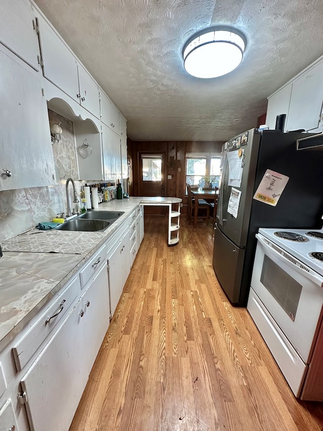 1501 Bishop St, Robert Lee, TX 76945 - kitchen featuring white electric range oven, light wood-style floors, a sink, white cabinets, and a textured ceiling