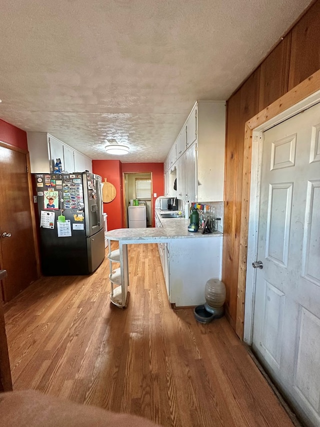 1501 Bishop St, Robert Lee, TX 76945 - kitchen featuring stainless steel fridge with ice dispenser, light wood-style floors, white cabinetry, a textured ceiling, and light countertops