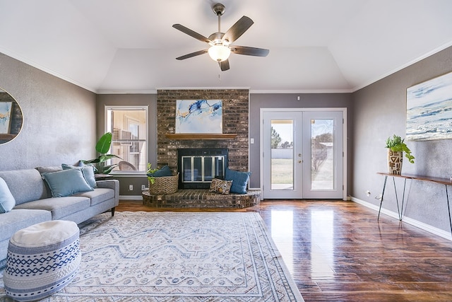 living room with wood finished floors, lofted ceiling, a fireplace, french doors, and crown molding