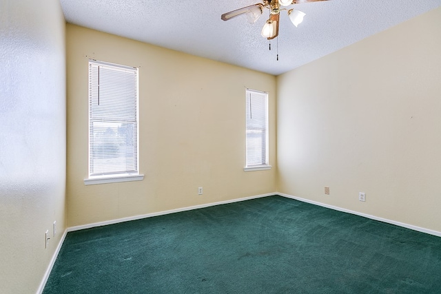 spare room featuring baseboards, dark carpet, a textured ceiling, and ceiling fan