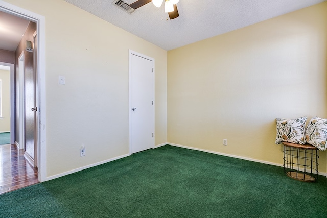 carpeted spare room with visible vents, baseboards, a textured ceiling, and a ceiling fan