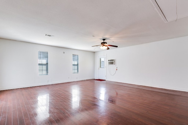 empty room featuring visible vents, ceiling fan, attic access, wood finished floors, and a textured ceiling