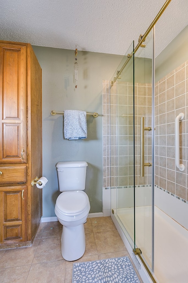 bathroom featuring a textured ceiling, toilet, a stall shower, and tile patterned flooring