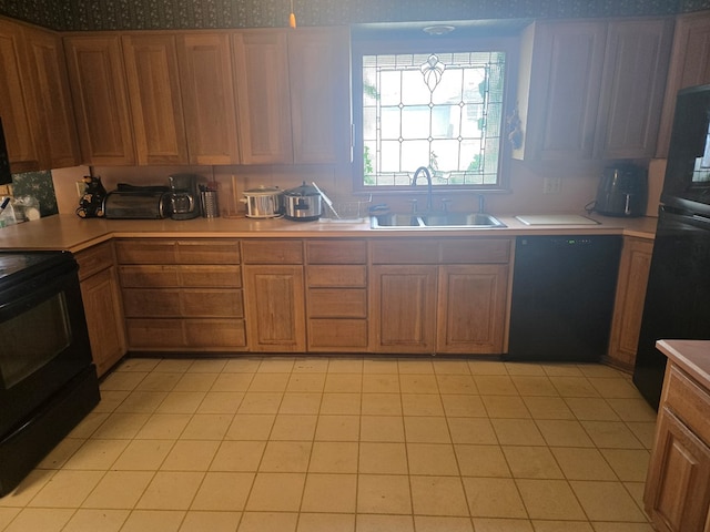 kitchen featuring black appliances, brown cabinetry, a sink, and light countertops