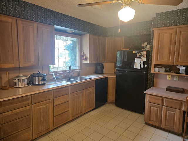 kitchen featuring light countertops, a sink, black appliances, and wallpapered walls