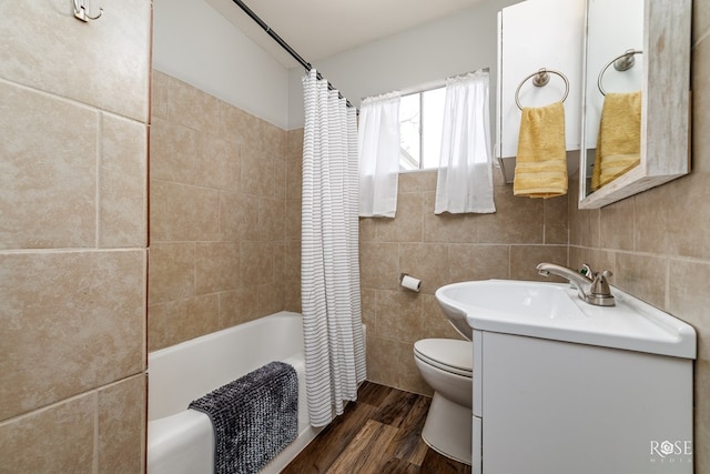 bathroom with wood finished floors, tile walls, shower / bath combo, toilet, and vanity