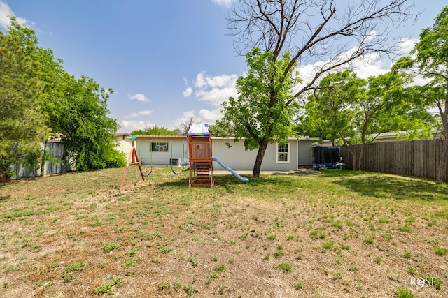 rear view of property featuring a fenced backyard, a yard, and a playground