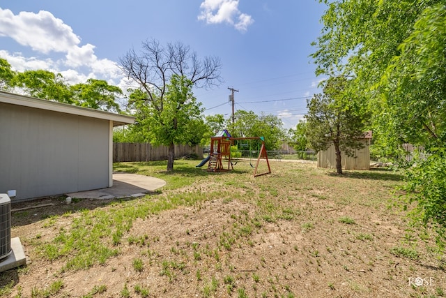view of yard featuring a fenced backyard, an outbuilding, a shed, and a playground