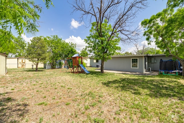 view of yard featuring fence, a playground, and a trampoline