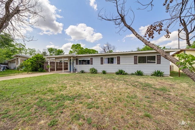 rear view of property featuring driveway, a yard, an attached carport, and fence