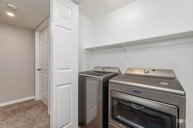 laundry area with light colored carpet, washing machine and clothes dryer, laundry area, and baseboards