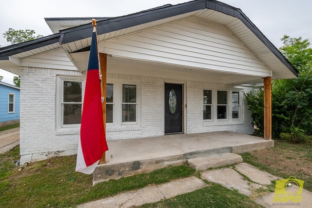 bungalow-style house featuring covered porch and brick siding