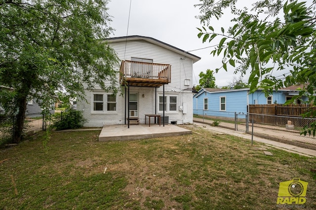rear view of property featuring a patio area, brick siding, a balcony, a yard, and a fenced backyard