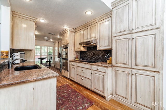3110 Palo Duro Dr, San Angelo, TX 76904 - kitchen with under cabinet range hood, tasteful backsplash, light wood-type flooring, stainless steel double oven, and recessed lighting