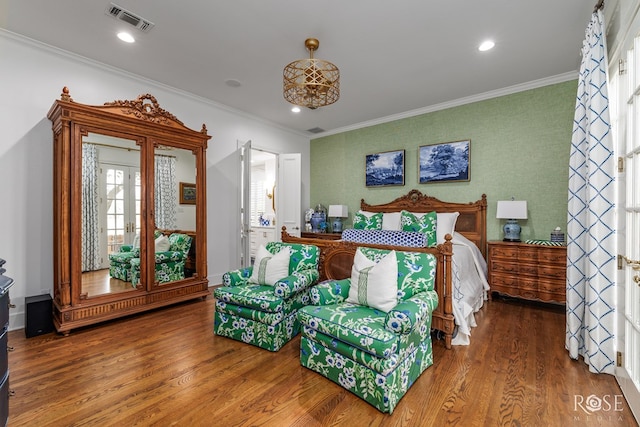 bedroom featuring visible vents, wood finished floors, and ornamental molding