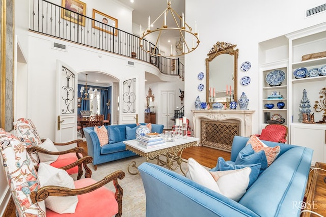 living area featuring visible vents, built in shelves, a notable chandelier, wood finished floors, and arched walkways