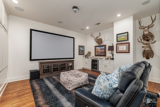 home theater with visible vents, baseboards, wine cooler, a dry bar, and light wood-style floors