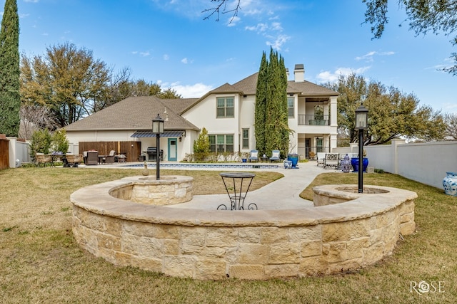 back of house with a fenced backyard, a balcony, a chimney, and a patio