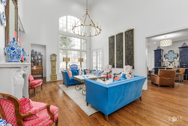 living area featuring a chandelier, a towering ceiling, and wood finished floors