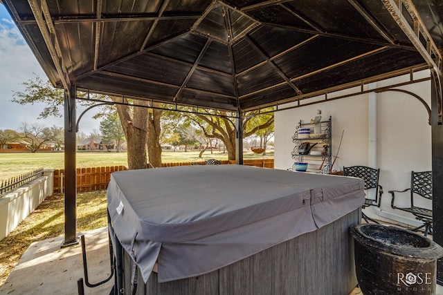 view of patio featuring a gazebo, fence, and a hot tub