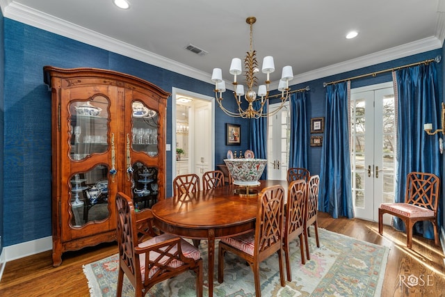 dining space with visible vents, french doors, an inviting chandelier, and wood finished floors