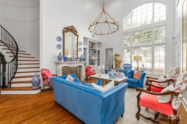 living area featuring built in features, wood finished floors, stairway, a high ceiling, and a chandelier