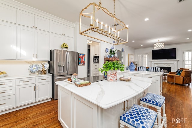 kitchen featuring stainless steel fridge with ice dispenser, ornamental molding, white cabinets, open floor plan, and a center island