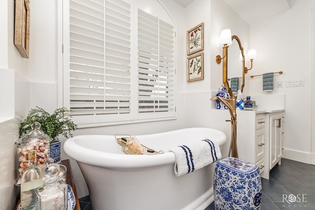 bathroom with tile patterned floors, vanity, baseboards, and a freestanding tub