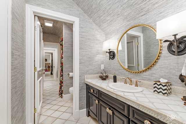 bathroom with tile patterned flooring, lofted ceiling, toilet, and vanity