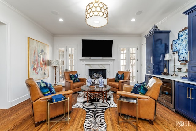 living area featuring french doors, a fireplace, crown molding, and wood finished floors