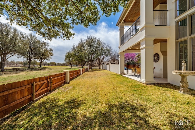 view of yard featuring a patio, a balcony, and a fenced backyard