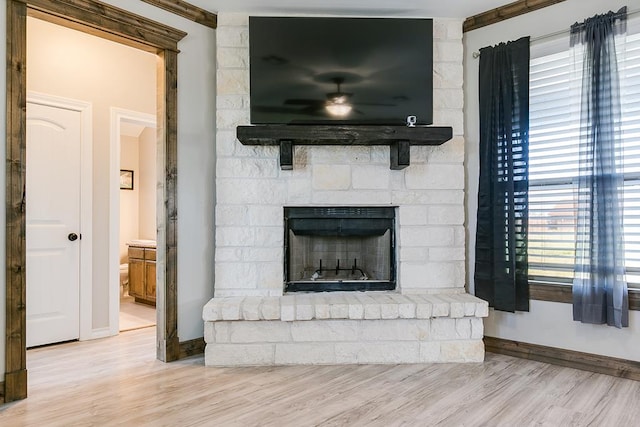 living room featuring ceiling fan, a large fireplace, and light hardwood / wood-style floors