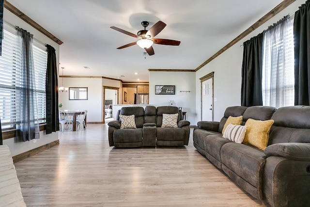 living room with ornamental molding, ceiling fan with notable chandelier, and light hardwood / wood-style flooring