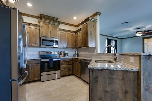 kitchen with sink, ornamental molding, kitchen peninsula, stainless steel appliances, and light stone countertops