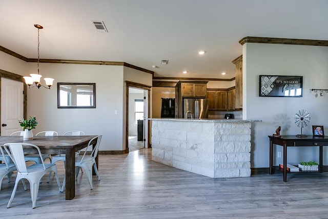 dining area with ornamental molding, a notable chandelier, and light hardwood / wood-style flooring