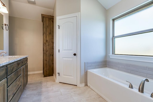 bathroom with vanity, tile patterned flooring, lofted ceiling, and a bathing tub