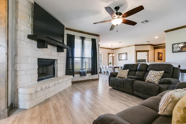 living room featuring crown molding, ceiling fan, a fireplace, and light hardwood / wood-style flooring