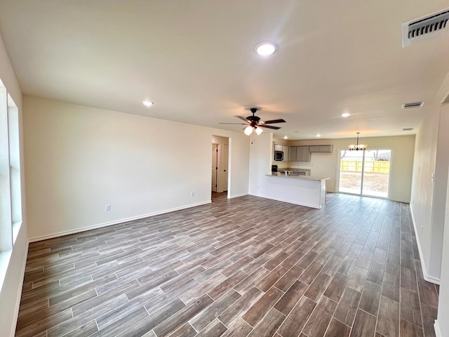 unfurnished living room featuring dark wood finished floors, visible vents, ceiling fan with notable chandelier, and recessed lighting