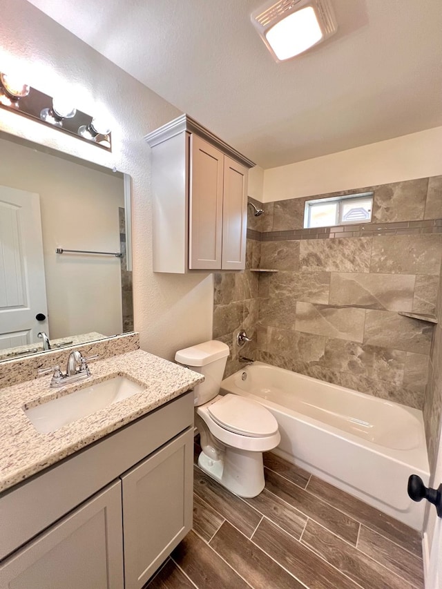 bathroom featuring wood tiled floor, toilet, shower / bathtub combination, a textured wall, and vanity