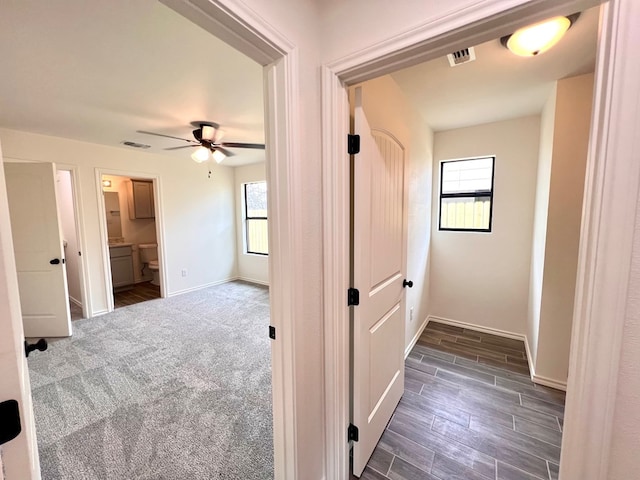 hallway with visible vents, baseboards, and wood tiled floor