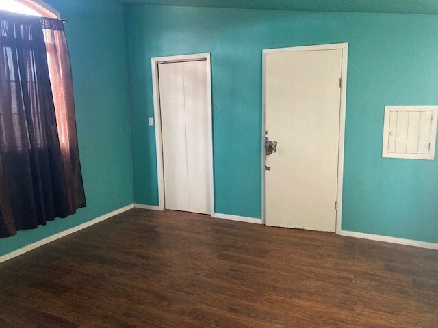 spare room with electric panel and dark hardwood / wood-style flooring