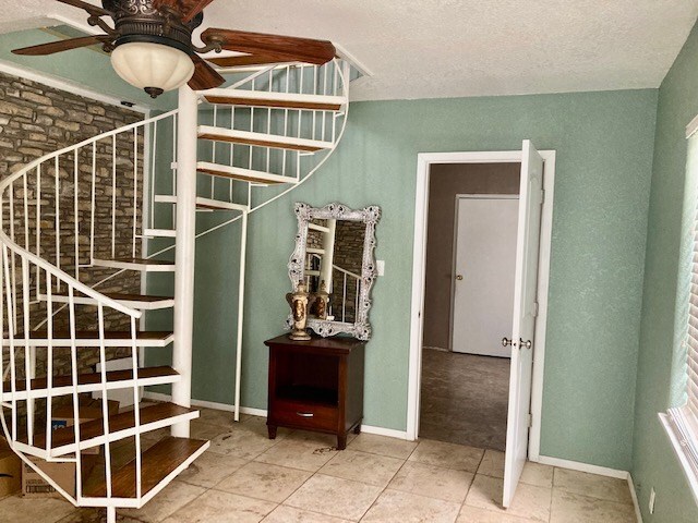 stairway featuring ceiling fan and tile patterned flooring