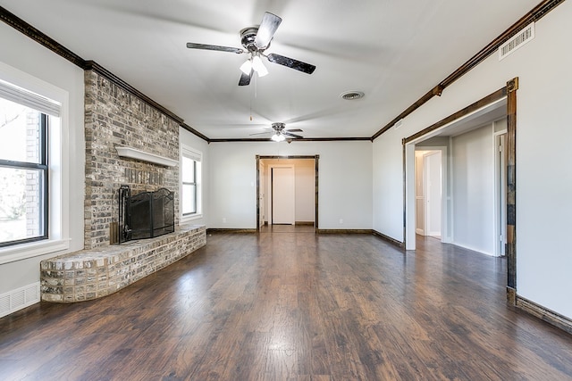 unfurnished living room with crown molding, ceiling fan, dark hardwood / wood-style flooring, and a brick fireplace