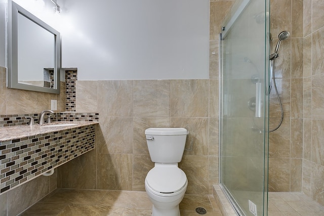 bathroom featuring sink, a tile shower, tile walls, and toilet