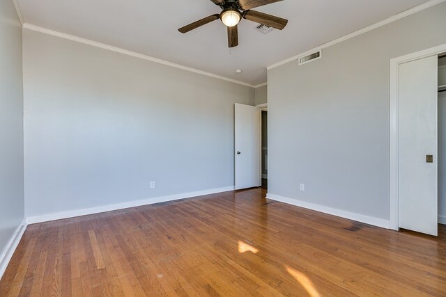 empty room with hardwood / wood-style flooring, ornamental molding, and ceiling fan