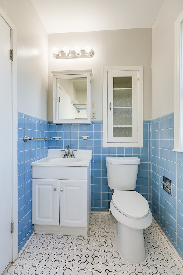 bathroom with vanity, toilet, tile patterned flooring, and tile walls