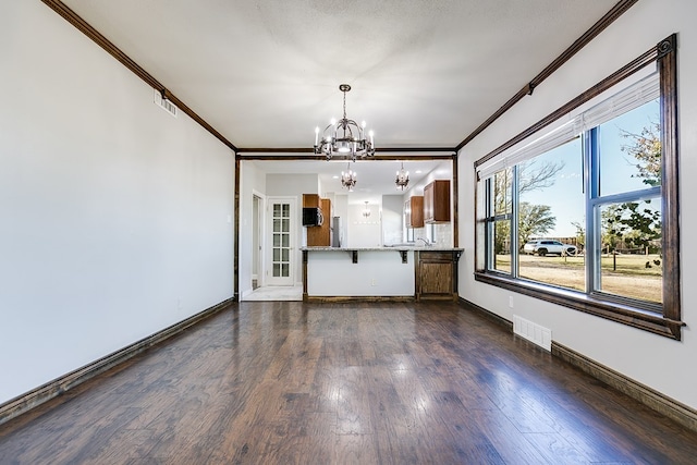 unfurnished living room with ornamental molding, dark hardwood / wood-style floors, and a chandelier